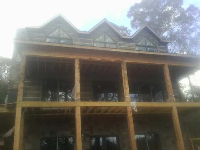 Dormers and porch framing on a large log home under construction — Roof Coating work by our crew in Severn
